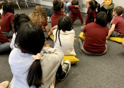 A kid raising their hand to answer teacher's question.